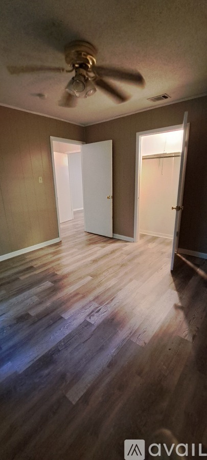 A room with a ceiling fan and wooden flooring.