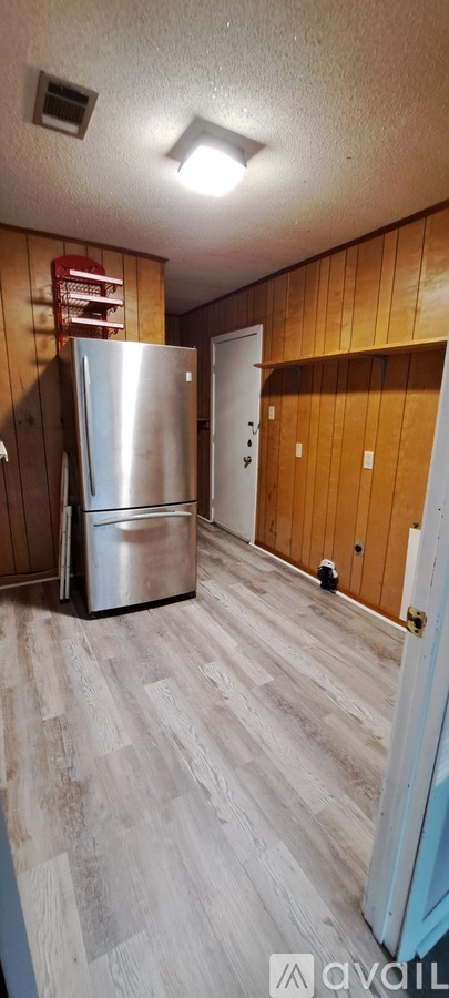 A kitchen with a refrigerator and a wooden wall.