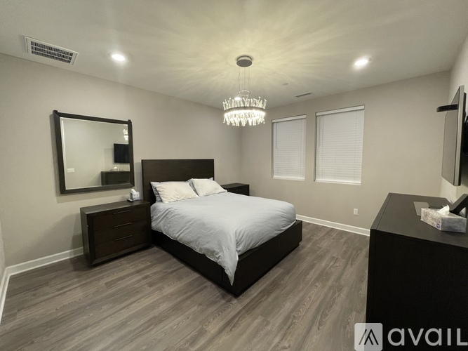 A bedroom with a large bed, a chandelier, and a mirror.