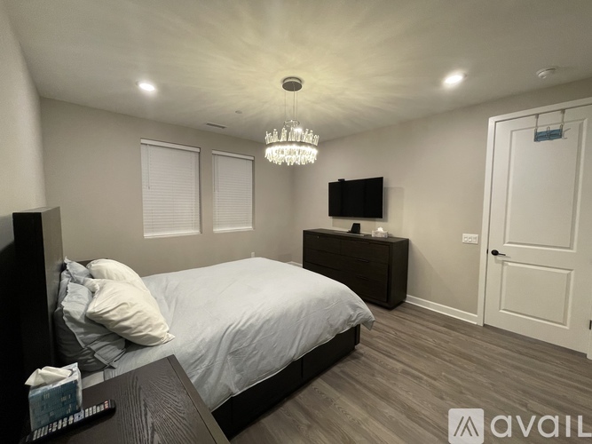 A bedroom with a bed, nightstand, and a chandelier.