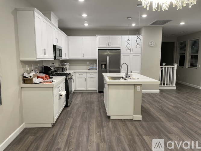 A modern kitchen with white cabinets and a wooden floor.