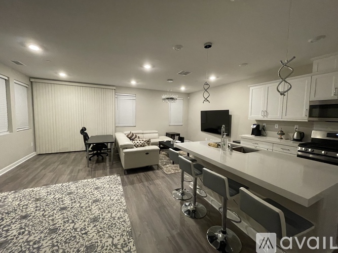 A modern kitchen and living room with a patterned rug on the floor.