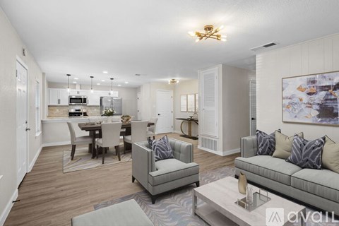 A living room with a grey couch and a dining table with chairs.