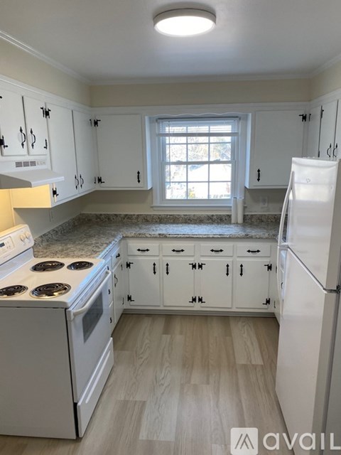 A kitchen with white cabinets and a white refrigerator.