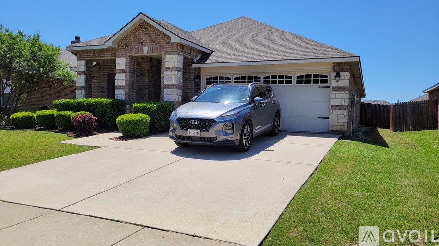 A silver car is parked in front of a house with a garage.