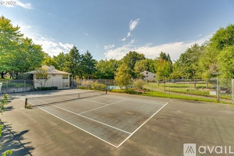 A tennis court surrounded by trees and a building in the background.