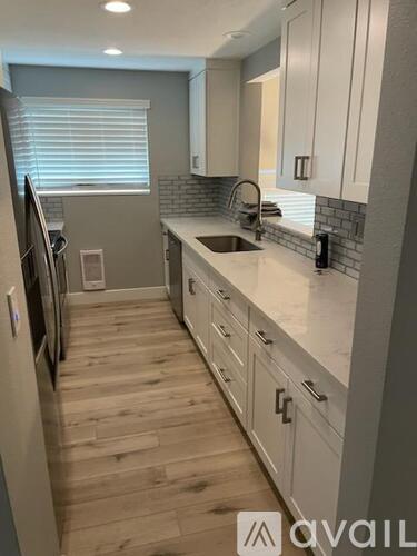A kitchen with white cabinets and a wooden floor.