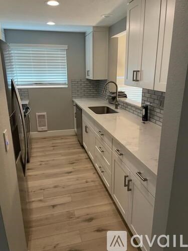 A kitchen with white cabinets and a wooden floor.