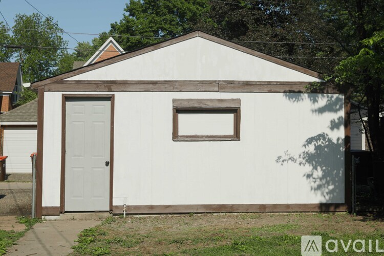 A small white building with a brown door and window.