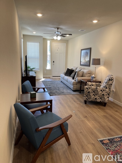 A living room with a couch, chairs, and a rug.