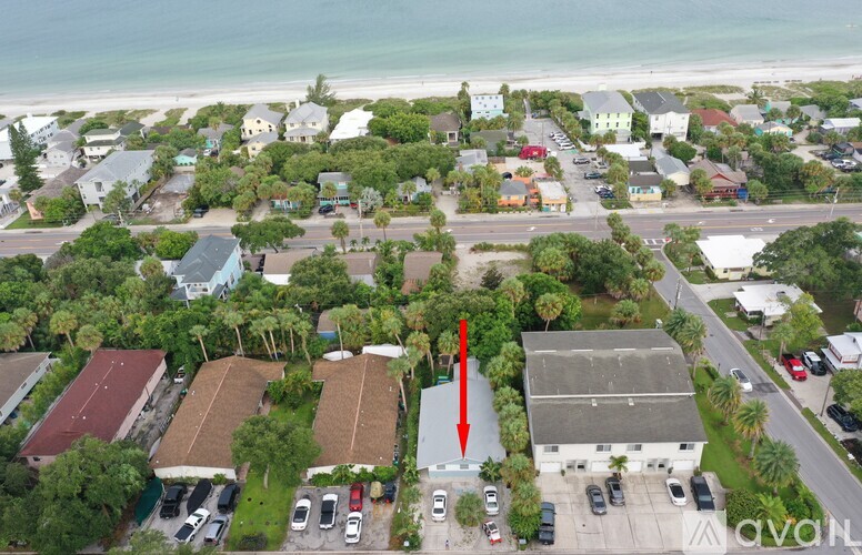 An aerial view of a beachfront neighborhood with a red arrow pointing to a specific building.