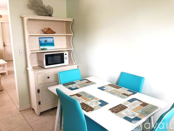 A white dining table with a white cabinet and a white microwave on top of it.