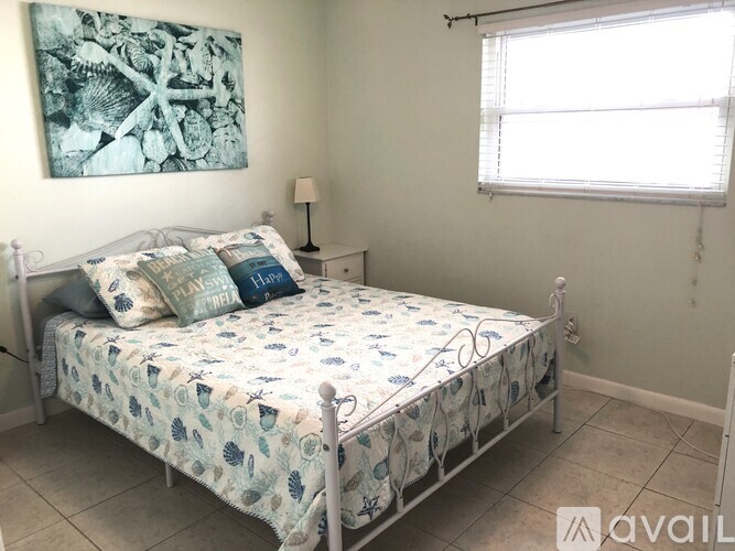 A bedroom with a bed, a nightstand, and a painting on the wall.