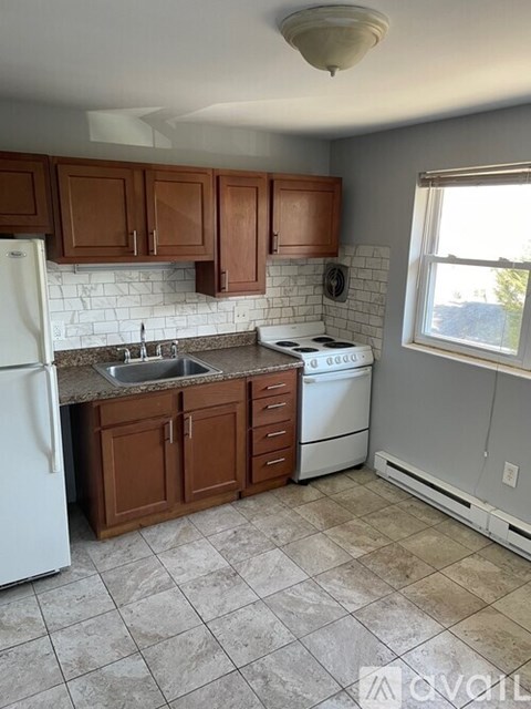 A kitchen with brown cabinets and a white refrigerator.