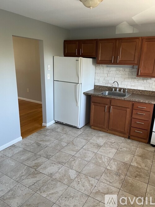 A kitchen with a white fridge and brown cabinets.