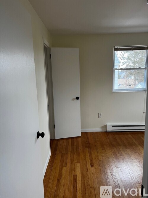 A room with a white door and wooden floors.
