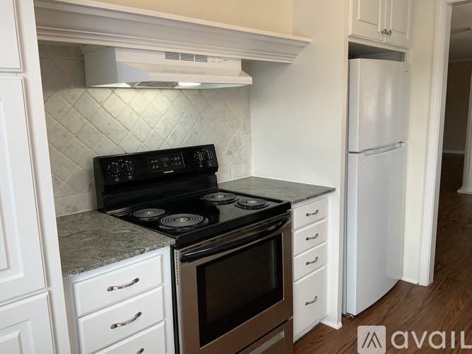 A kitchen with a black stove top oven and white cabinets.