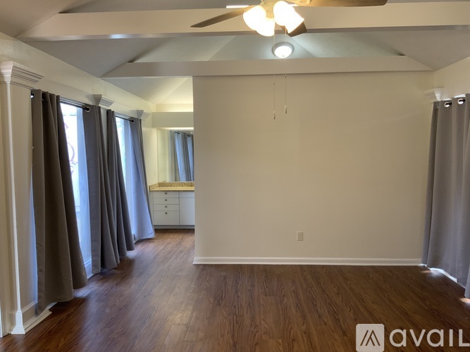 A spacious room with a ceiling fan and wooden flooring.