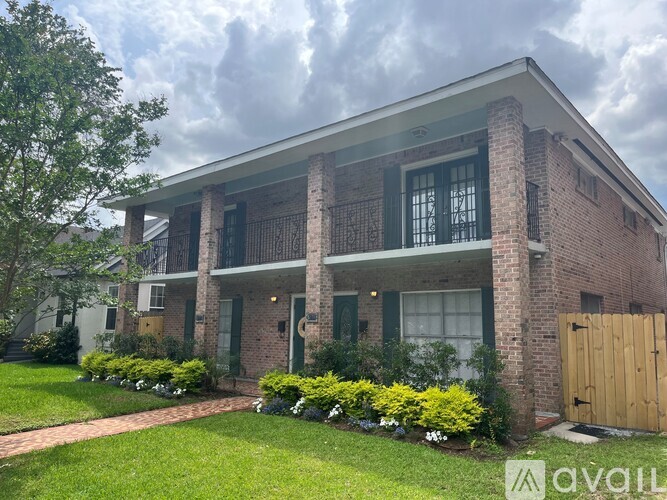 A brick house with a balcony and green shutters.