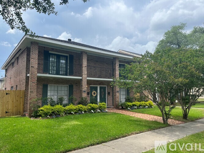 A house with a green door and windows surrounded by a grassy area and trees.