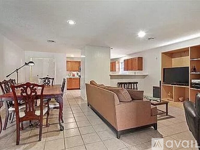 A living room with a brown couch and a wooden dining table.
