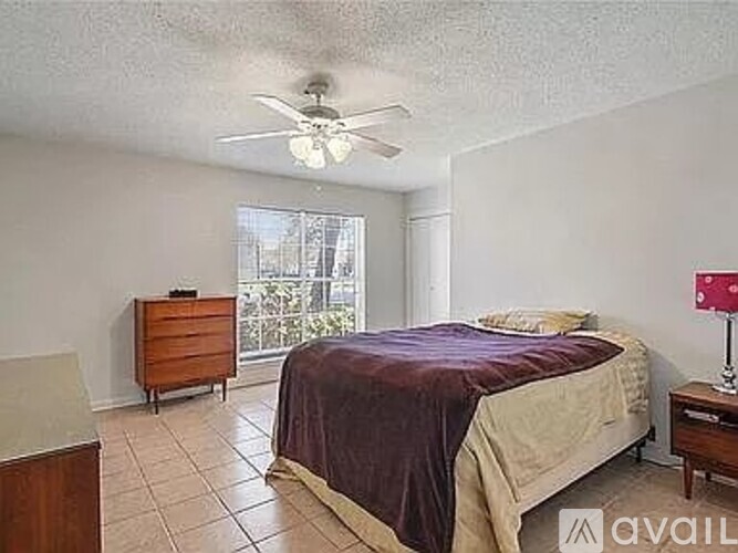 A bedroom with a bed, dresser, and ceiling fan.