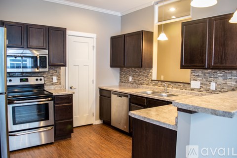 A kitchen with dark brown cabinets and a granite counter top.