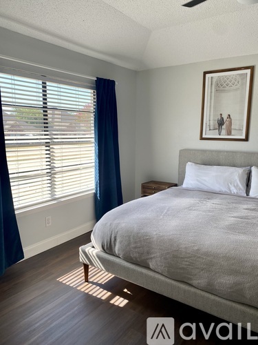 A bedroom with a bed, a nightstand, and a painting on the wall.