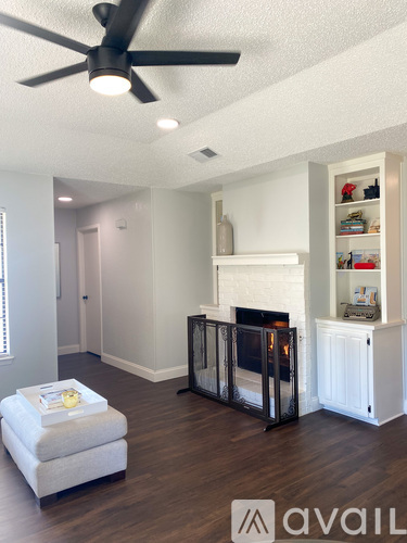 A living room with a fireplace and a fan on the ceiling.
