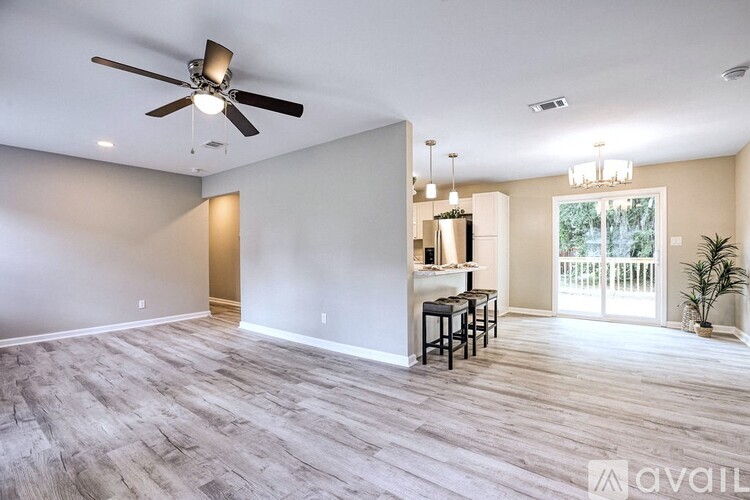 A spacious room with a ceiling fan and a bar area.