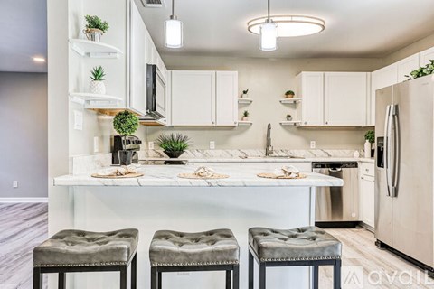 A kitchen with white cabinets and a marble countertop.