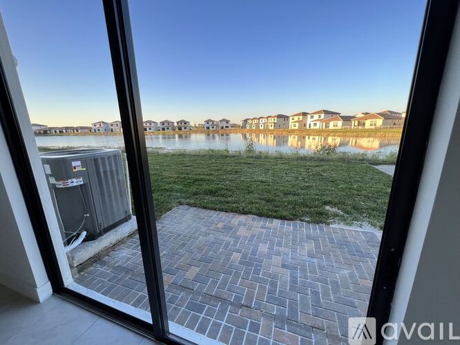 A view from a window looking out to a grassy area and a body of water with houses in the distance.