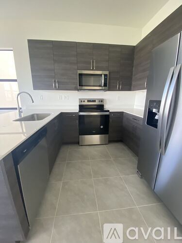 A modern kitchen with a stainless steel refrigerator and a microwave above the stove.