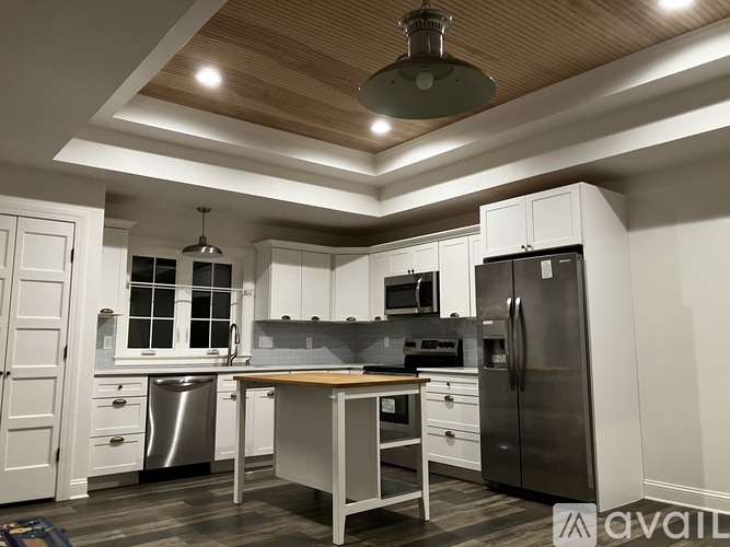 A modern kitchen with a wooden ceiling and stainless steel appliances.