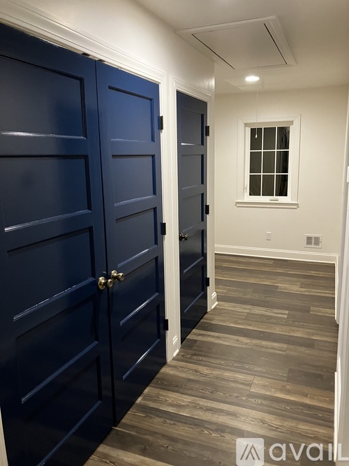 A hallway with dark blue doors and a window.