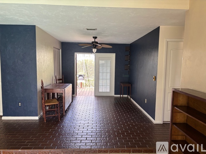 A room with a ceiling fan and brick flooring.