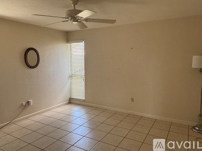 A room with a ceiling fan and a window with blinds.