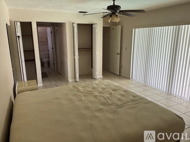 A bedroom with a bed, a ceiling fan, and a closet with a sliding door.