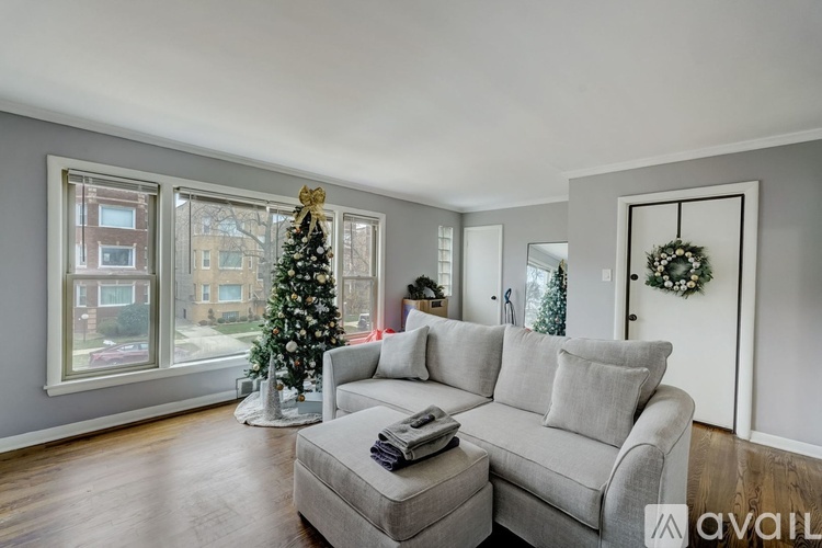 A living room with a grey couch and a Christmas tree.