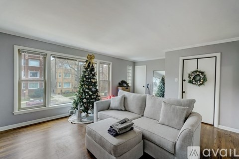 A living room with a grey couch and a Christmas tree.