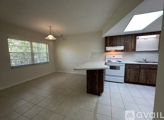 A kitchen with a white stove top oven and wooden cabinets.