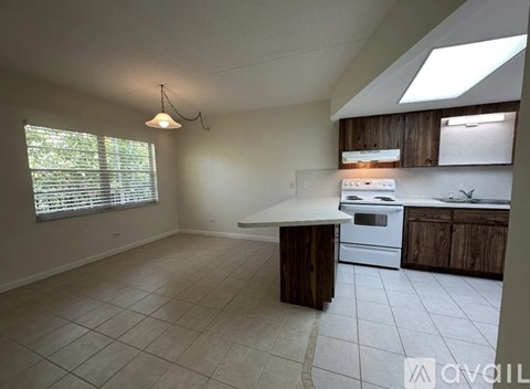 A kitchen with a white stove top oven and wooden cabinets.