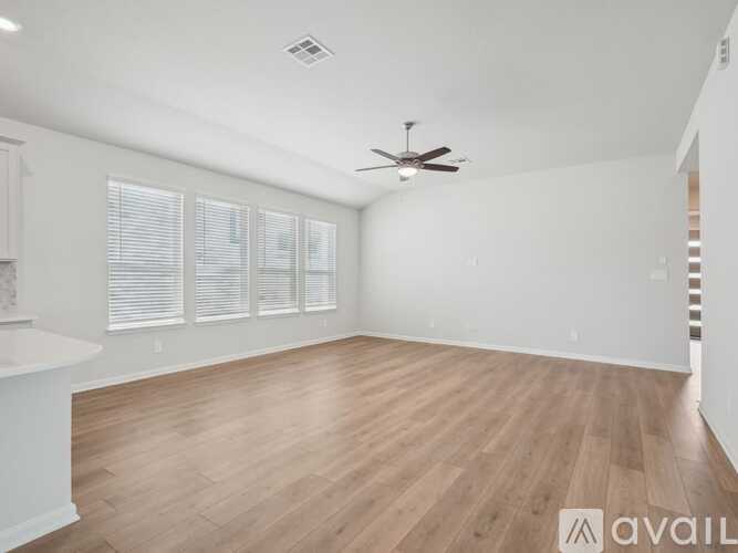 A spacious room with wooden flooring and a ceiling fan.