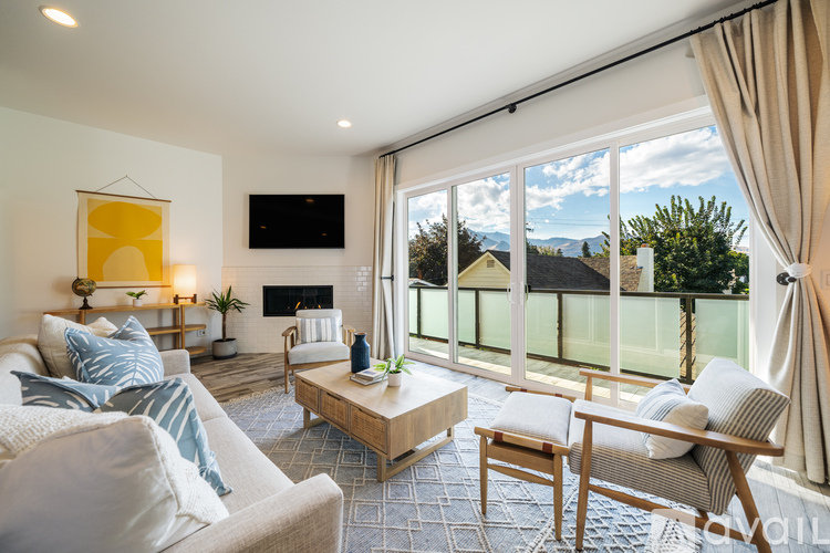 A living room with a fireplace and a large window overlooking the mountains.