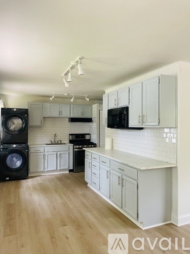 A modern kitchen with white cabinets and a wooden floor.