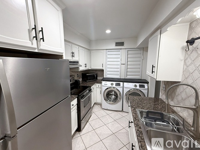 A kitchen with white cabinets and a stainless steel refrigerator.