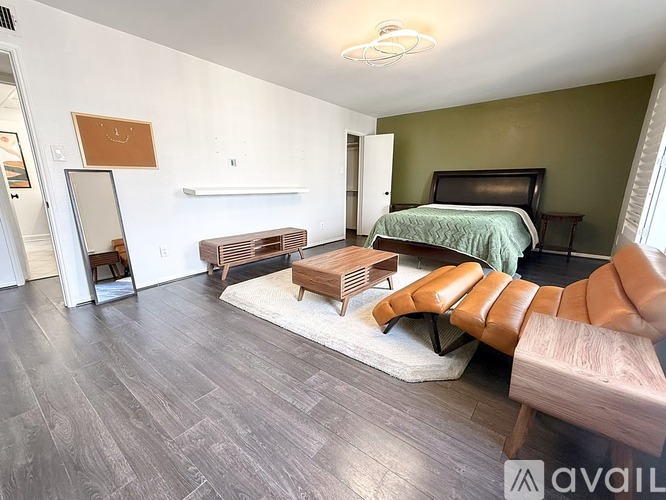 A bedroom with a bed, a bench, and a mirror.