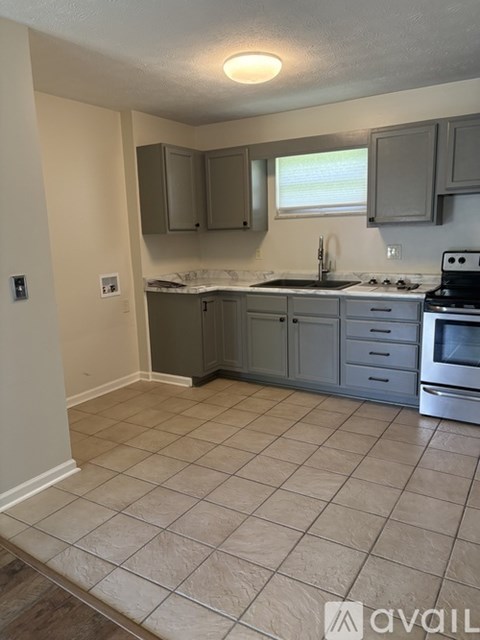 A kitchen with tile flooring and a stove top oven.