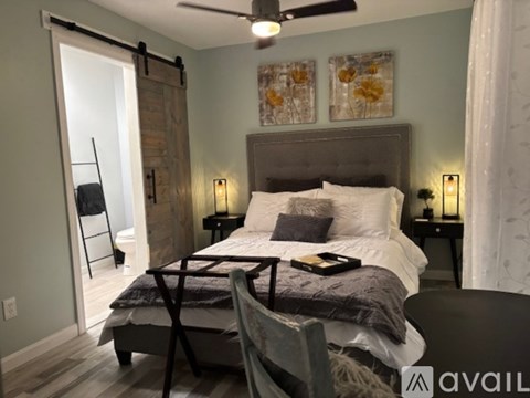 A bedroom with a bed, a chair, and a painting on the wall.
