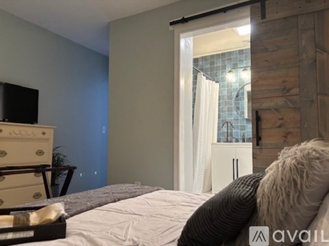 A bedroom with a bed, a dresser, and a window with curtains.